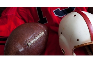 A collection of vintage American football equipment, including a red jersey, an old football, and a white helmet.