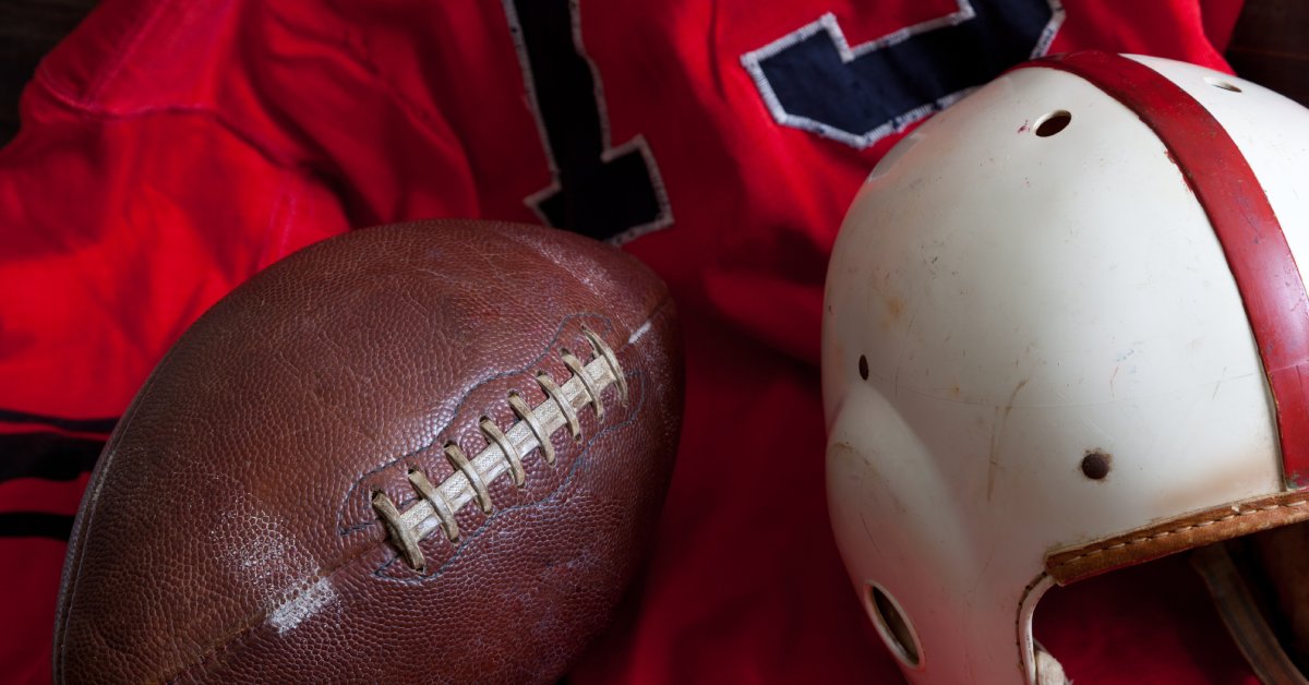 A collection of vintage American football equipment, including a red jersey, an old football, and a white helmet.