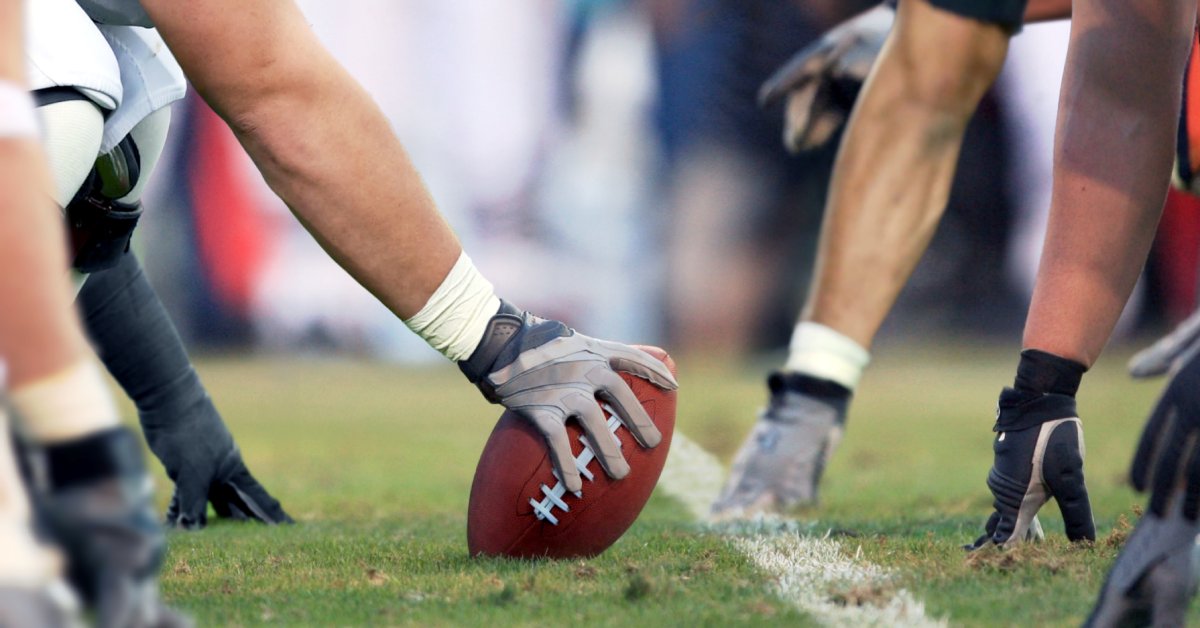 A close-up view of the line of scrimmage of an American football play with the center holding the ball ready to snap.